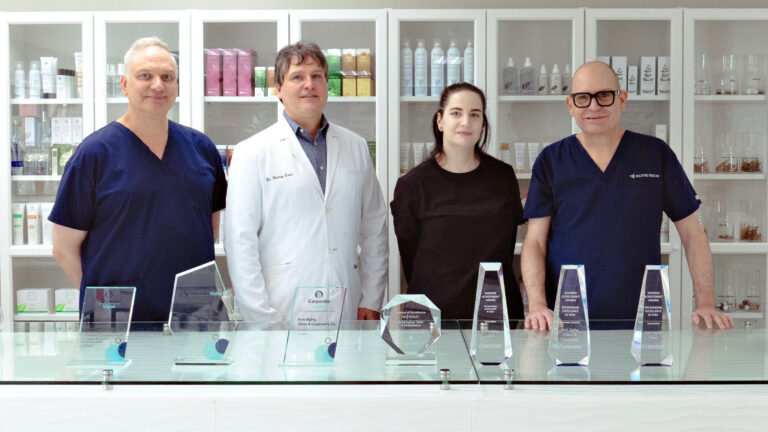 Four professionals standing behind a counter with multiple awards displayed