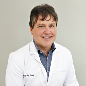 Smiling medical professional in white coat against plain background