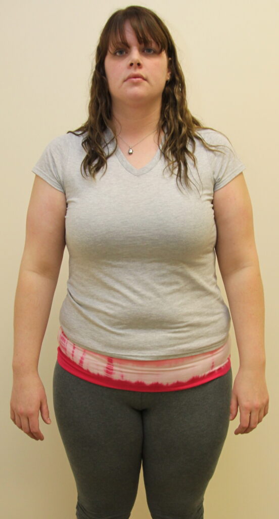 Woman in casual attire stands against a plain background