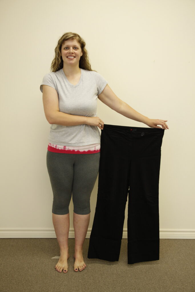 Woman proudly holding her previous larger pants after weight loss