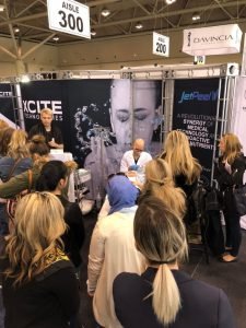 Crowd gathered at a skincare technology booth at a trade show