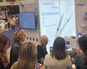 People at a dermatology trade show booth discussing needle-free injection technology