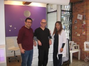 Three people standing in a modern dental clinic reception area