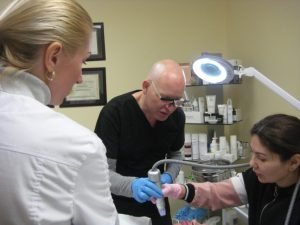 Three professionals performing a skincare treatment in a clinic