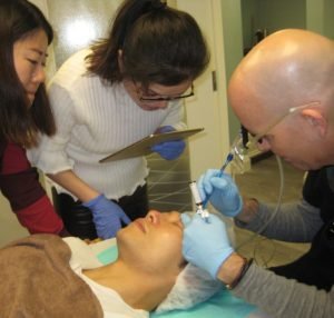 Team performing cosmetic procedure on a patient in clinic