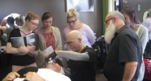 Barbering workshop with instructor demonstrating shaving technique