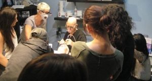 Group gathered around a tattoo procedure demonstration