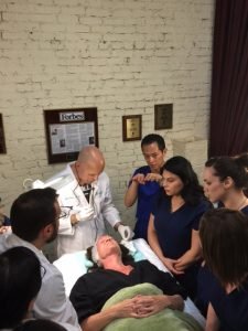 Group of medical professionals learning facial treatment techniques from an expert