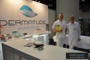 Dermatude Canada exhibition booth with two representatives at a trade show