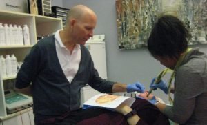 Instructor guiding student in permanent makeup application at beauty training class